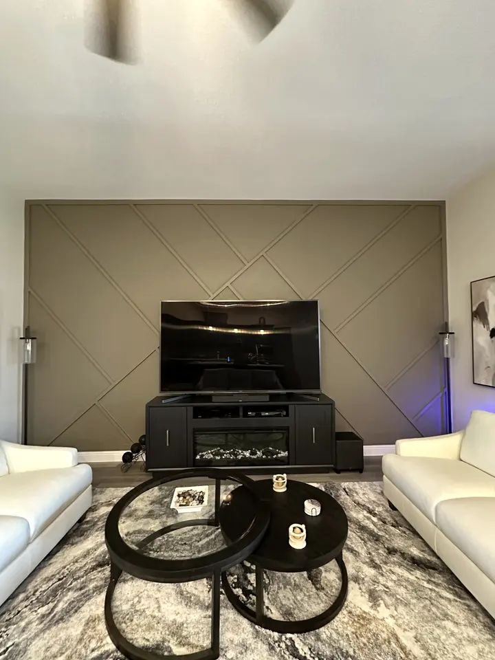Diagonal panel accent wall painted taupe behind a media console