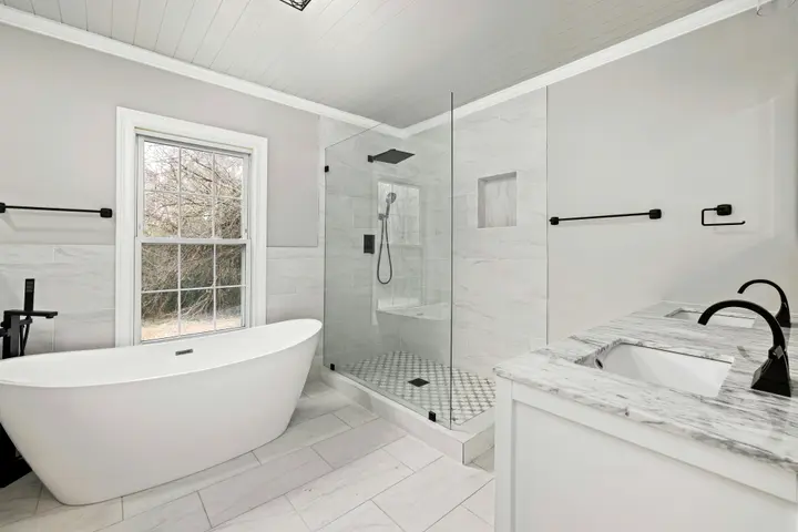 White bathroom with a freestanding tub, glass shower and marble vanity top