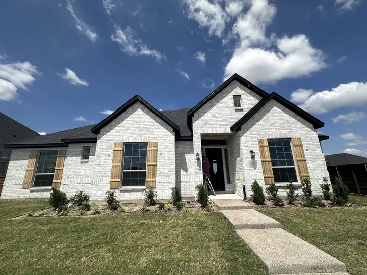 Limewashed white brick house with black trim, new cedar shutters and a painter at the front door
