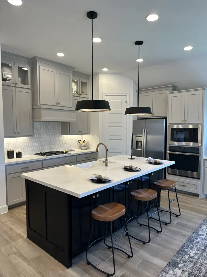 Kitchen with a navy island, white quartz top, black pendants and gray shaker cabinets