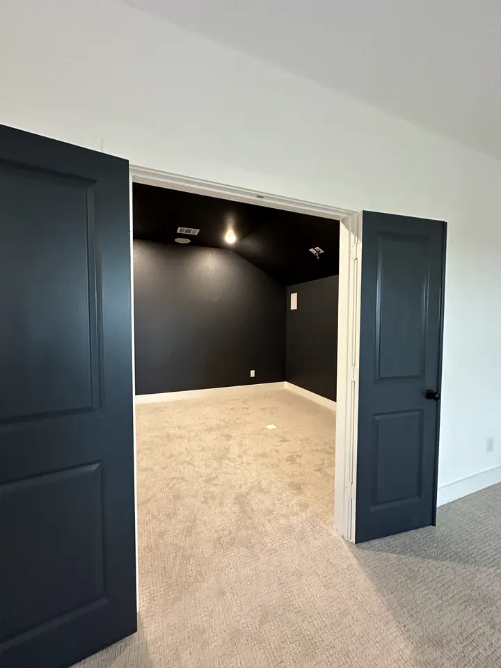 Double doors painted deep navy opening into a dark media room