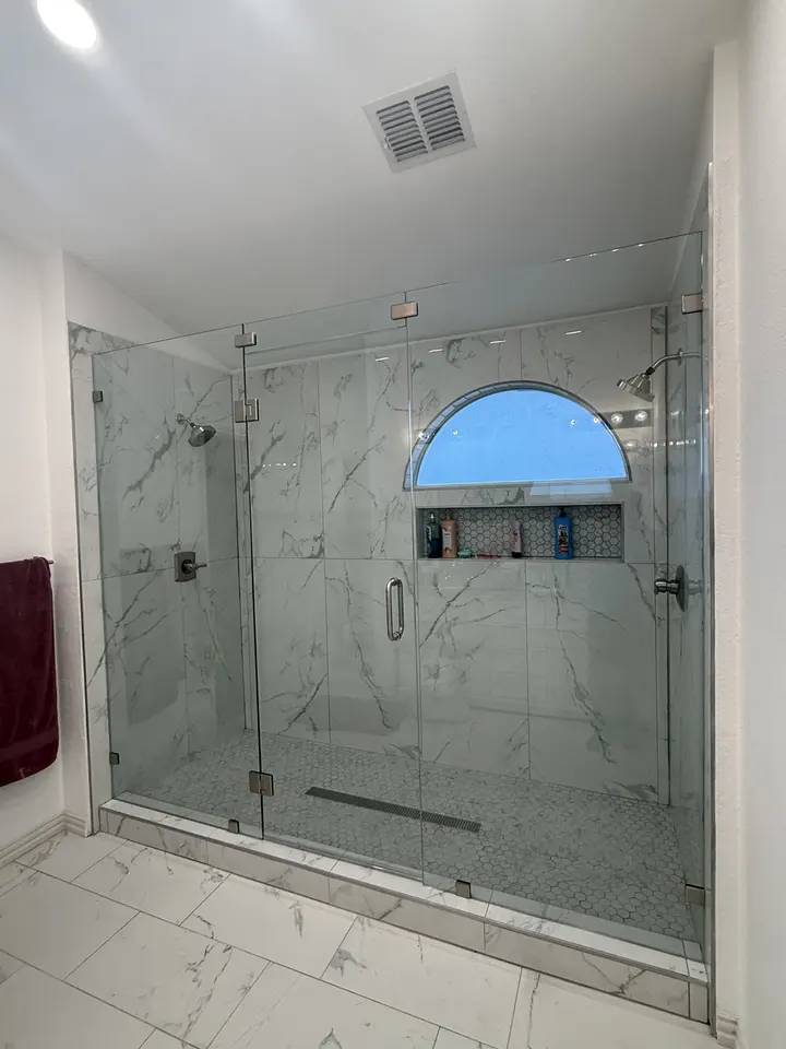 Marble-look shower with an arched window, linear drain and frameless glass door
